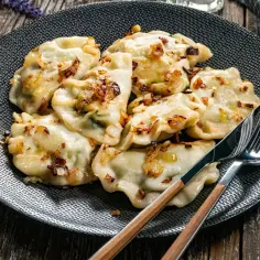 Pyszne pierogi z cebulką na talerzu. Zastanawiasz się, ile gotować pierogi, by były idealne? Te wyglądają na gotowe!