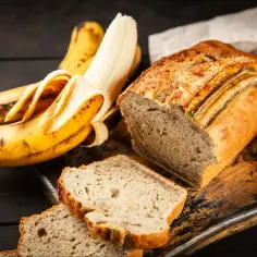 Pyszne, wilgotne ciasto bananowe, które zawsze się udaje. Obok leżą dojrzałe banany, gotowe do upieczenia.