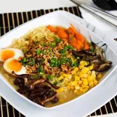 Apetyczny tantanmen z jajkiem na pół, kukurydzą, marchewką i grzybami shiitake.