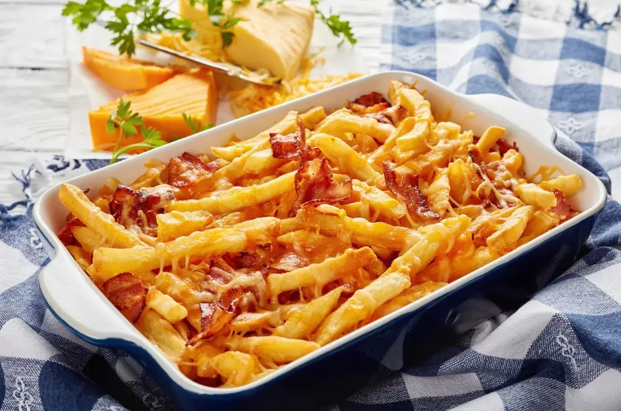 Zapiekane frytki z serem i chrupiącym boczkiem, podane w naczyniu, wyglądają apetycznie.