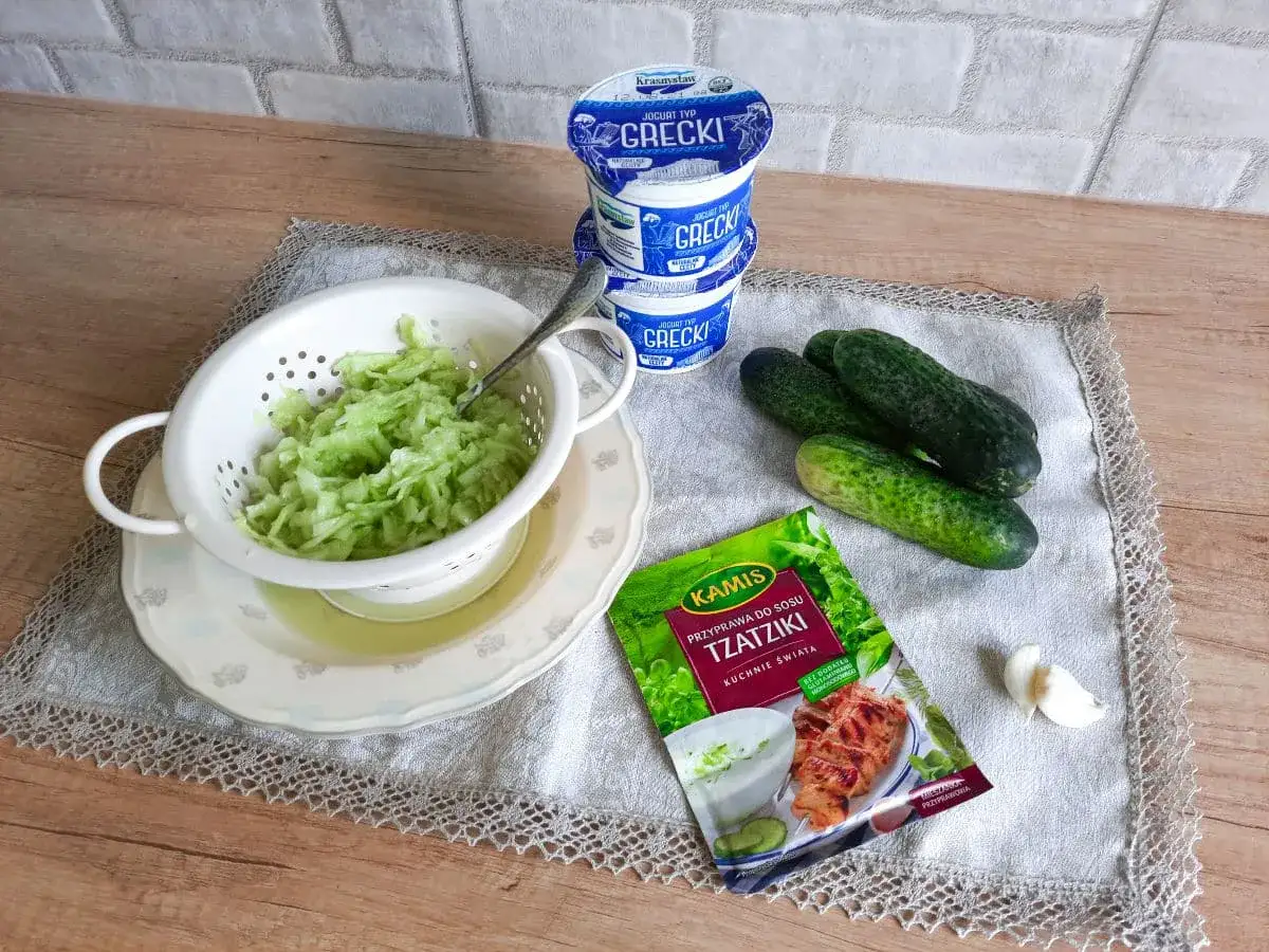Składniki na sos tzatziki: starty ogórek, jogurt grecki, przyprawa Kamisu i czosnek.