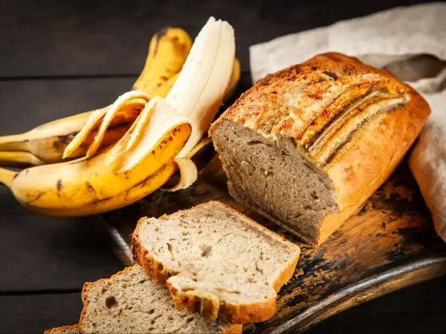 Pyszne, wilgotne ciasto bananowe, które zawsze się udaje. Obok leżą dojrzałe banany, gotowe do upieczenia.